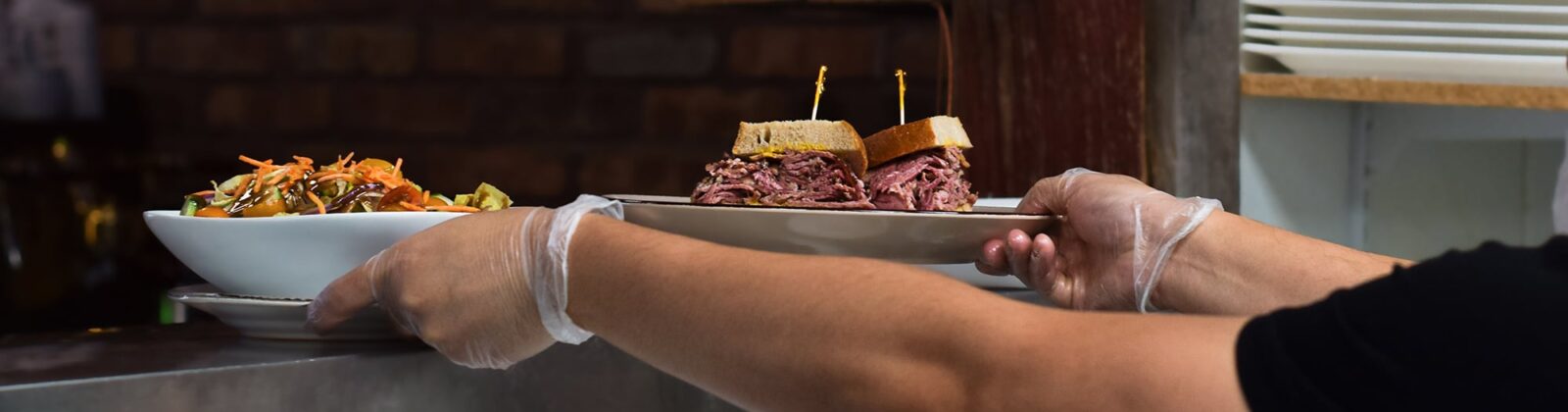 chef serving plated food with gloves