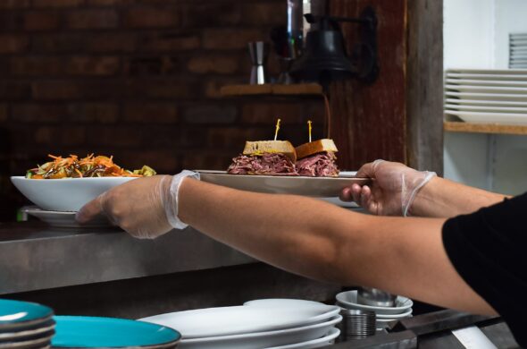 chef serving plated food with gloves